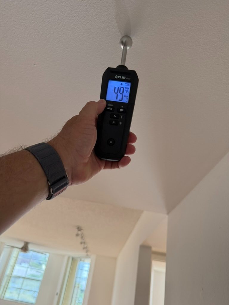 Moisture meter evaluating a ceiling surface as part of the water intrusion investigation.