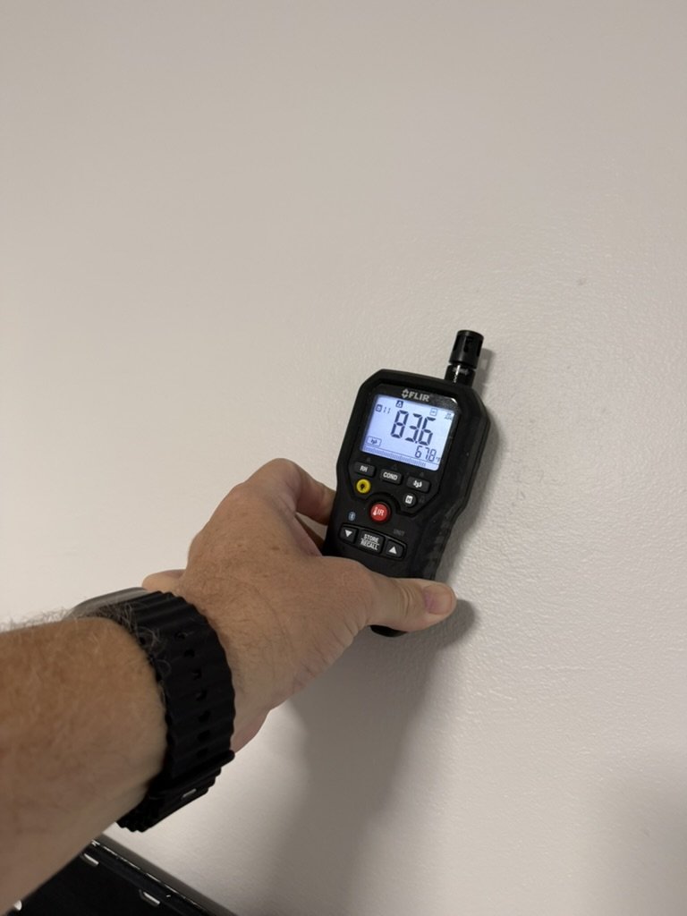 FLIR handheld moisture meter checking an interior surface for moisture during the roof leak investigation.