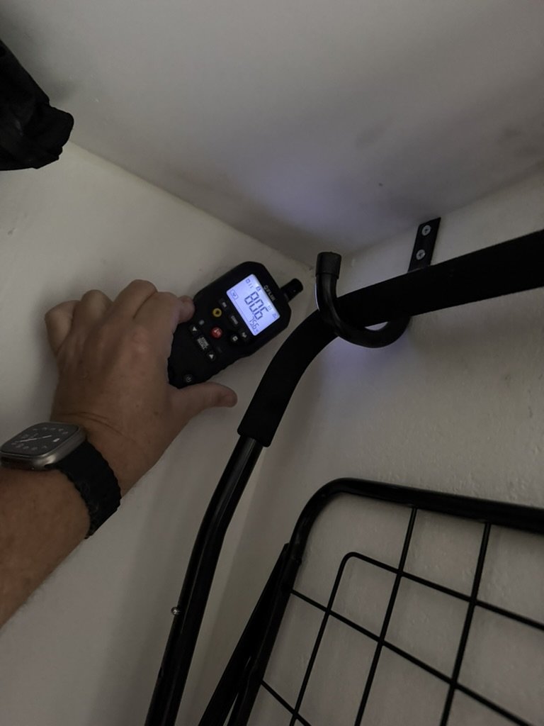 FLIR handheld moisture meter checking a closet ceiling corner for moisture.