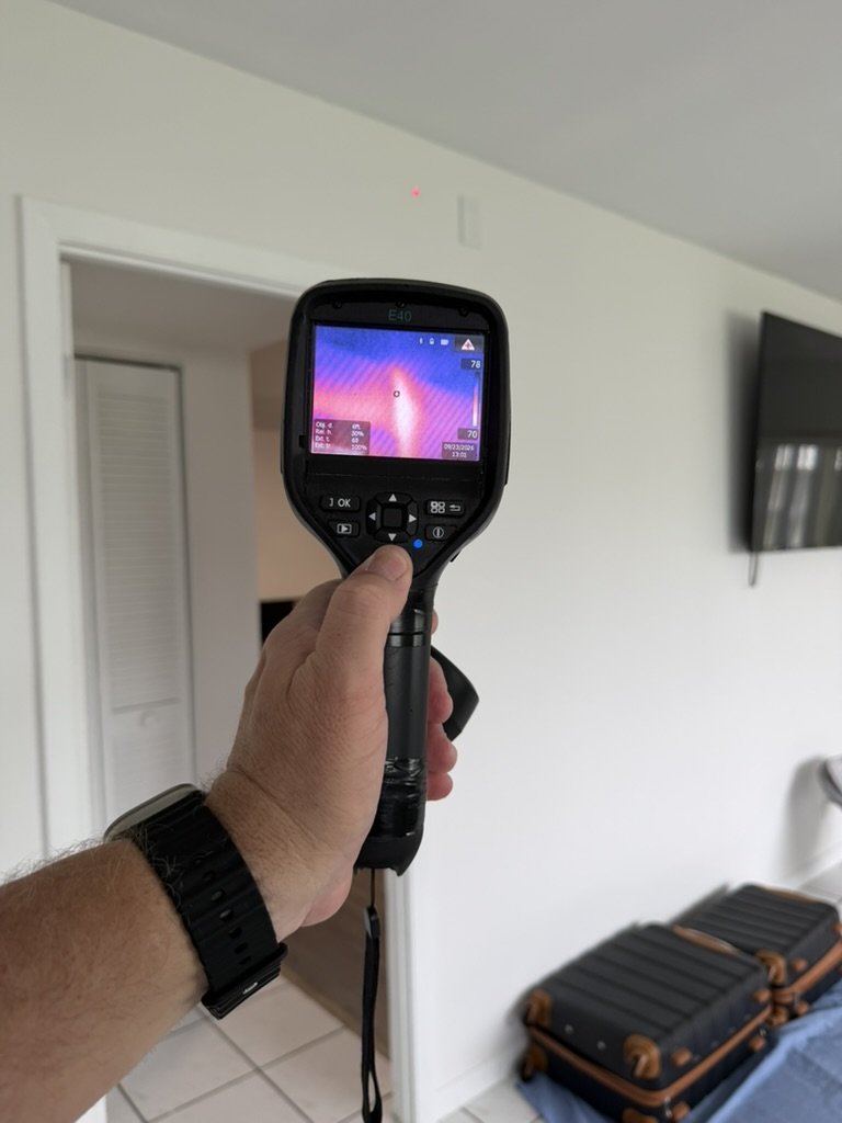 FLIR E40 thermal imaging camera scanning the upper wall and ceiling in the living area.