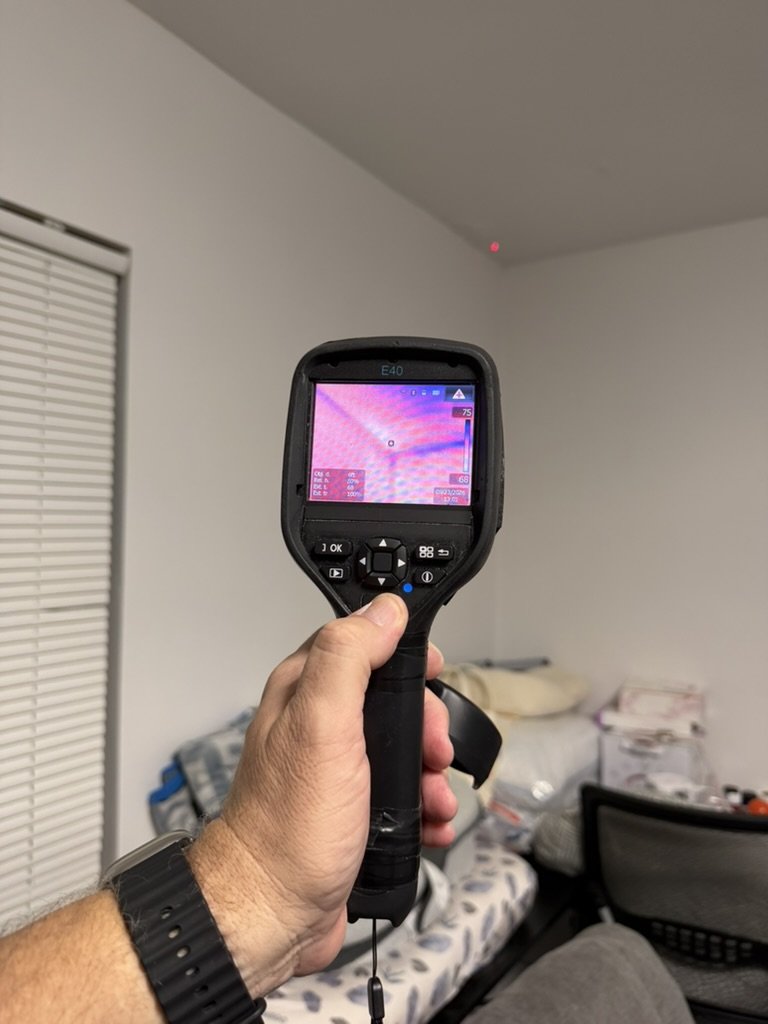 FLIR E40 thermal imaging camera scanning a bedroom ceiling corner.