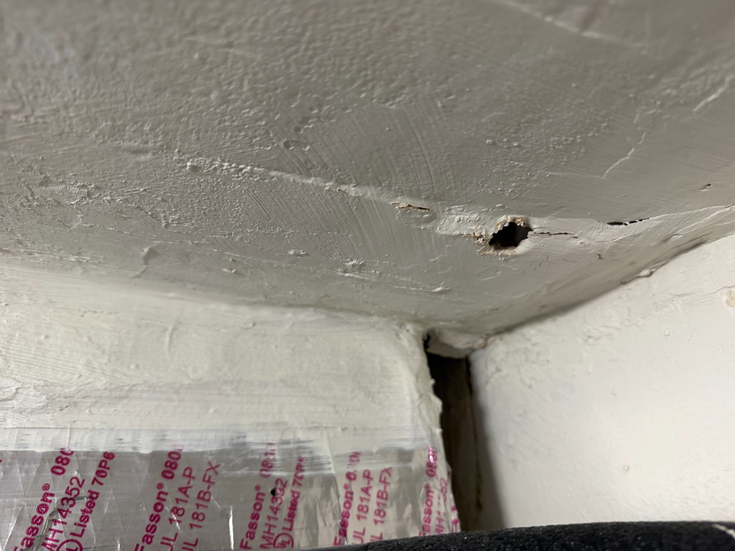 Ceiling penetration and cracked drywall seam near the AC closet ceiling-to-wall transition.