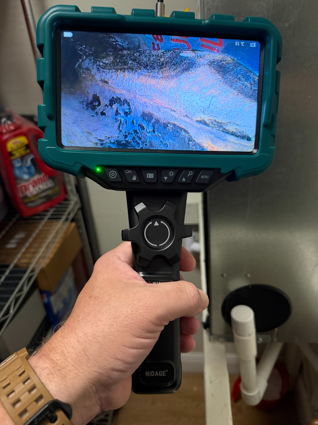 NIDAGE borescope inspection camera being used to visually examine a limited-access area behind the air handler.