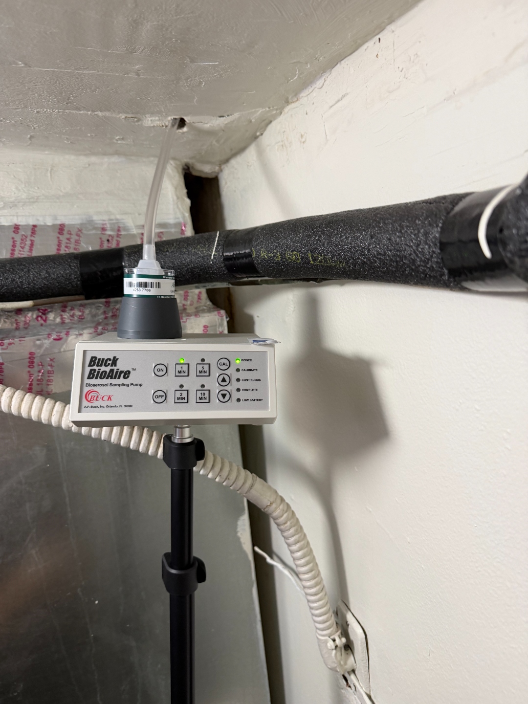 Buck BioAire bioaerosol sampling pump collecting an air sample near the AC closet ceiling.